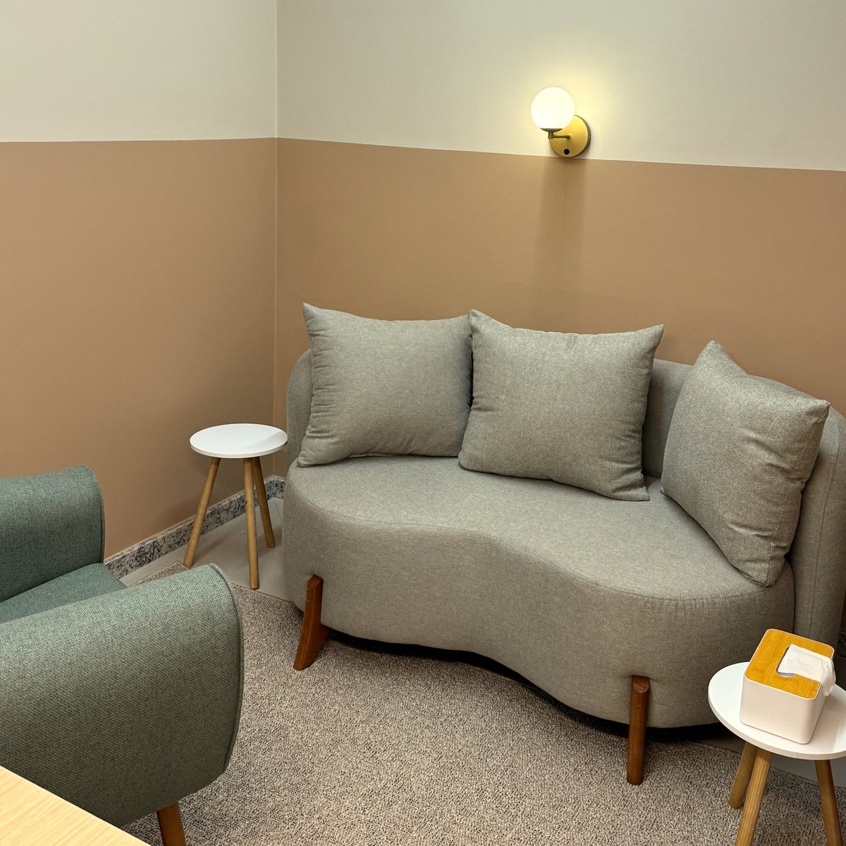 Consultório real do PsicoHub com sofá cinza, poltrona verde e iluminação acolhedora