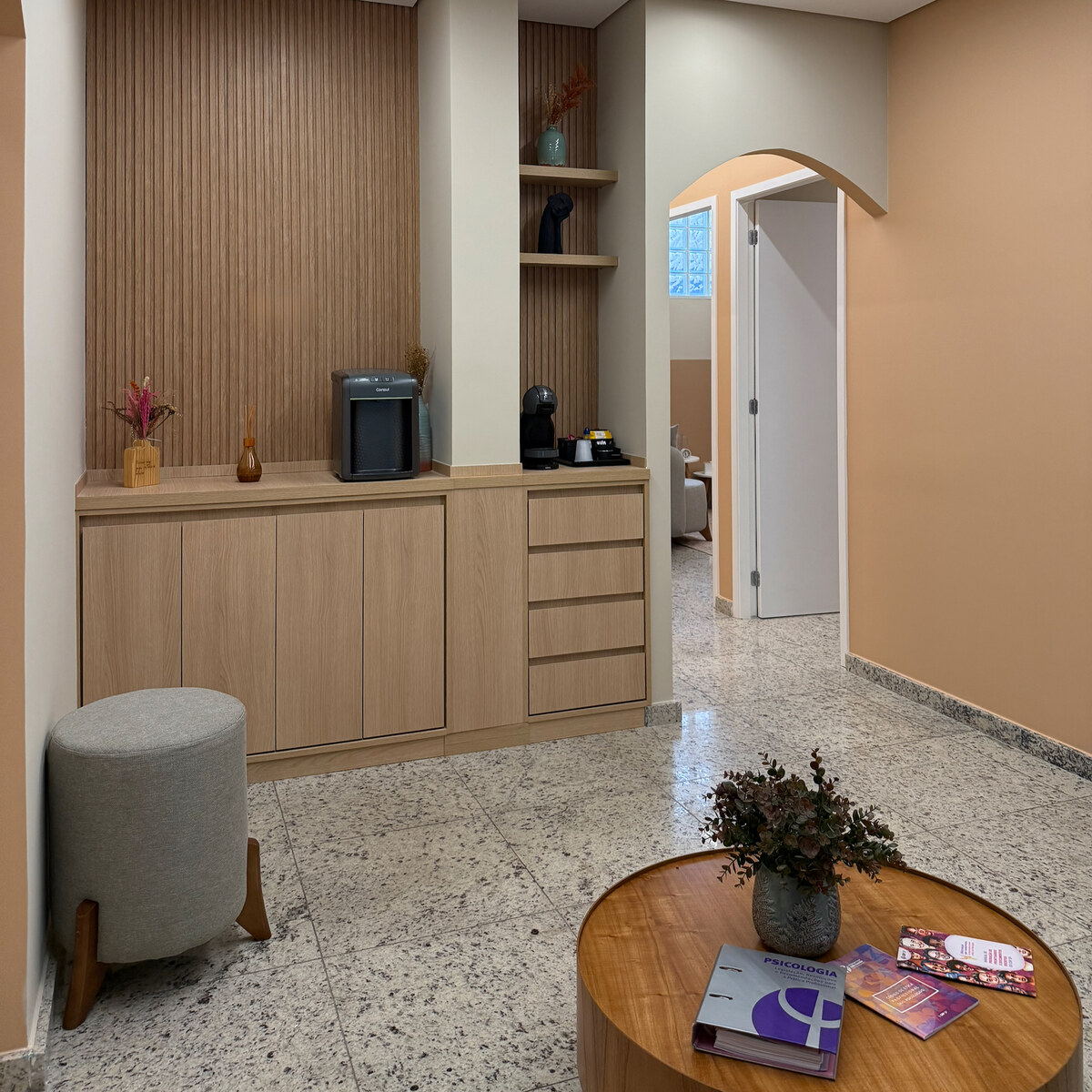Recepção do PsicoHub com mesa de centro, copa e entrada dos consultórios
